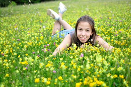 Smiling girl resting on the green grass and flowers. の写真素材