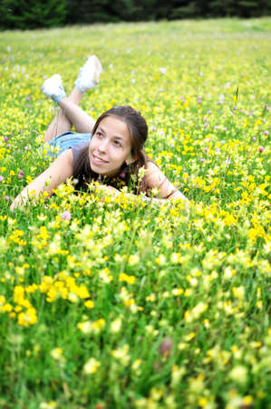 Smiling girl resting on the green grass and flowers. の写真素材