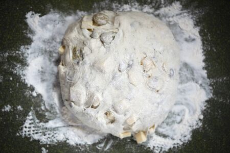 Artichoke cheese bread dough on a cutting board with flour