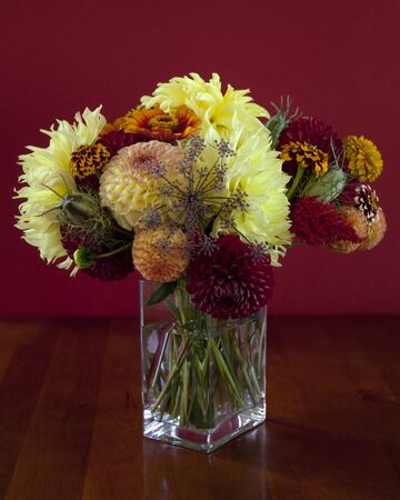 A bouquet of beautiful flowers on a cherry table with red backgroundの写真素材