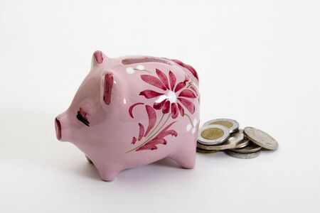 A cute, pink, piggybank pooping coins isolated on a white background の写真素材