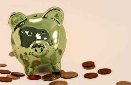 Green piggy bank with change scattered aroundの写真素材
