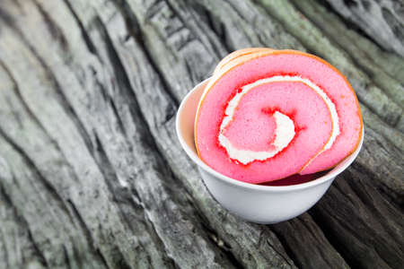 Cake roll in cup on wood backgroundの写真素材