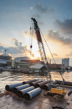 Iron pipe material and crane on raft for construction siteの写真素材