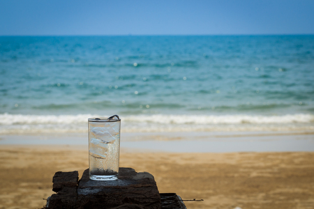 Glass with cold mineral water on the beachの写真素材