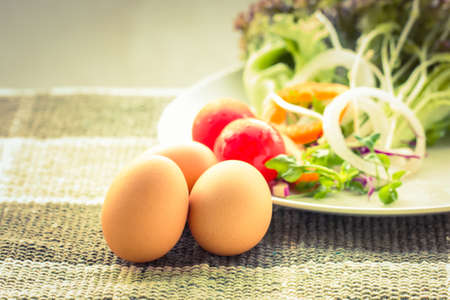 Three eggs with vegetable on matの写真素材