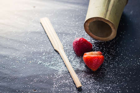 Strawberry with sugar on dark woodenの写真素材