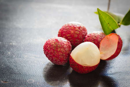 Lychee with leaves on a wooden table.の写真素材