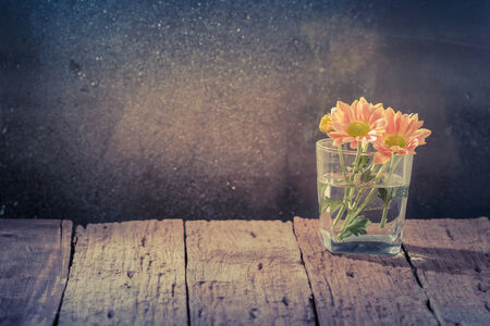 Daisy flower in glass on wooden table over grunge background,vintageの写真素材