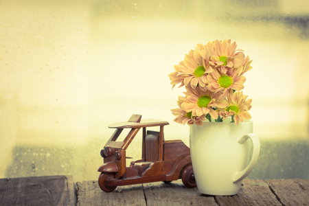 Pink daisy flower in white cup on wooden table over grunge backgroundの写真素材