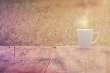 Steaming coffee cup on wood table. grass backgroundの写真素材