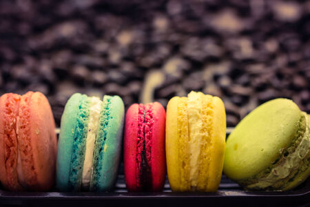 macaroons and coffee beans on wooden table, vintage stylized photo