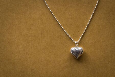 Beautiful heart shaped. silver pendant on paper textureの写真素材