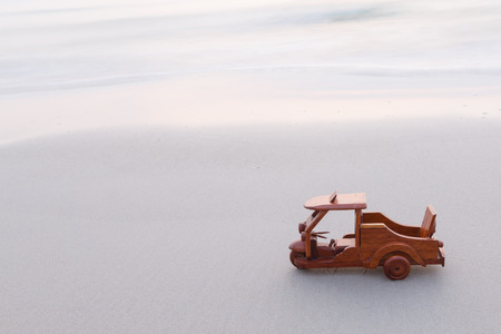 Small wooden toy car (Tuk Tuk Thailand) on beachの写真素材