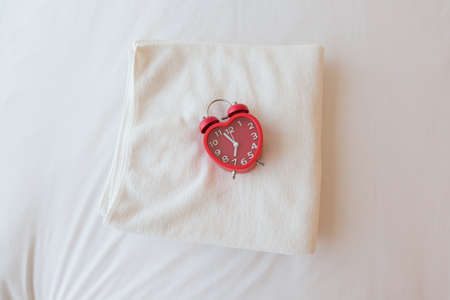 Red alarm clock on white towelの写真素材
