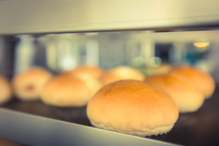 Delicious buns with crust on blurred bakery indoor background.の写真素材