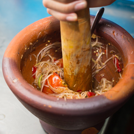 making of green papaya salad, som tam, thai food, ingredients are mixing and pounding in a mortar.の写真素材