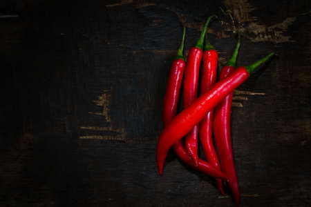 Still life with red chili peppers on dark wood