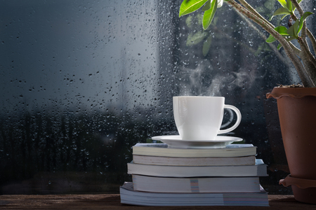 Cup of coffee with book beside rainyの写真素材
