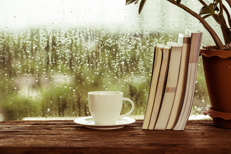 Cup of coffee with book beside rainyの写真素材