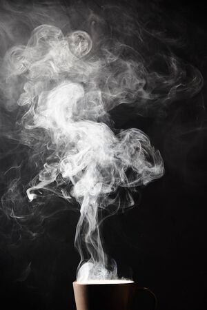 Steaming coffee cup on dark background, White smoke on dark