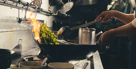 Chef stir fry busy cooking in kitchen. Chef stir fry the food in a frying pan, smoke and splatter...
