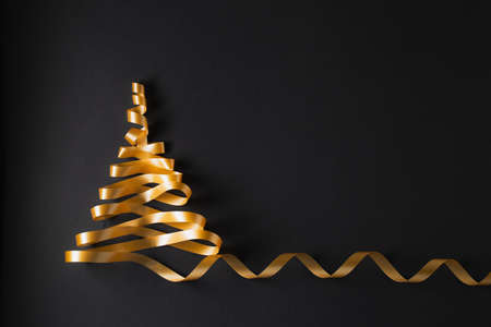Christmas tree made of gold ribbon  on black backgroundの写真素材