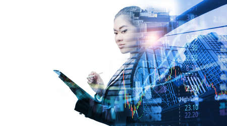 Business, people and technology concept - Smart Asian businesswoman with tablet pc computer over city buildings and graph stock market, double exposure effectの写真素材