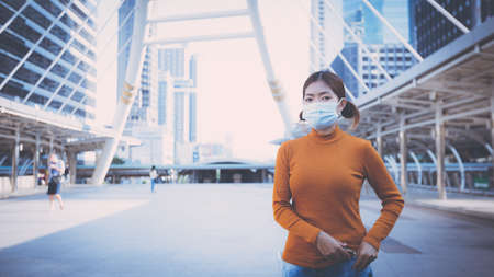 Young woman wearing protective face mask outdoors in city street. New Normal life after COVID-19 and health protocols to avoid infections and the virus spread in public spaces. Thailandの写真素材