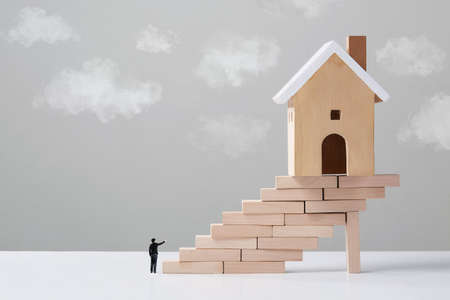 Businessman looking stairs to target house buying concept, House wooden modelの写真素材