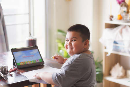 Cute Asian kid learning class study online  from tablet at home .Social distancing concept