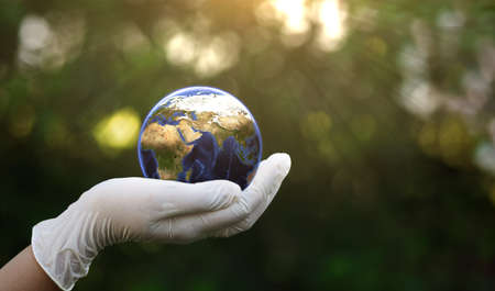 Hand in white glove holding Earth globe on bokeh background. Elements of this image furnished by NASAの写真素材
