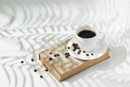 Hot black coffee with coffee beans on modern shadowの写真素材