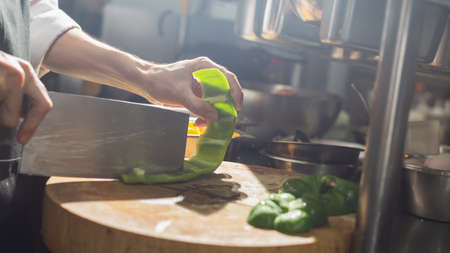 Chef chopping Bell chili with knife in kitchenの写真素材