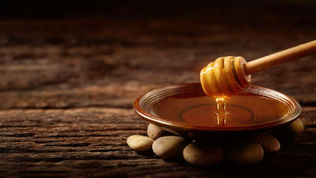 Honey drips from a honey dipper in a bowl. Healthy natural honey dipped close-up wooden spoon honeyの写真素材