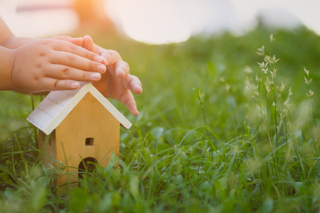 Children hands covering wood house model.House  insurance conceptの写真素材