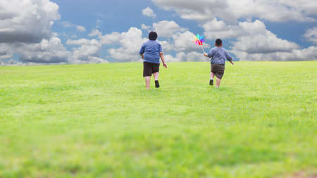 Asian brother and his younger brother running outdoor on meadowの写真素材