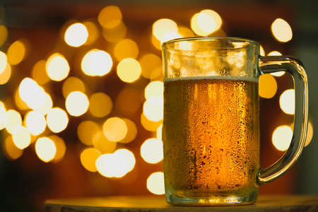 Beer in mug on wooden table with bokeh backgroundの写真素材