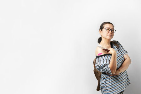 Asian woman ready for safe travel journey. Portrait of happy holding passport, smiling and showing arms after receiving COVID-19 vaccine. Coronavirus vaccination conceptの写真素材
