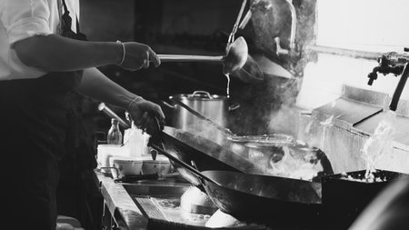 Chef stir fry busy cooking in kitchen. Chef stir fry the food in a frying pan, smoke and splatter the sauce in the kitchen.の写真素材