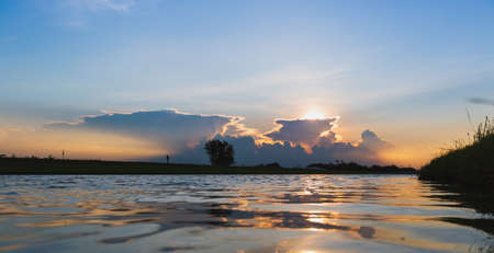 Clouds with reflection on river at sunset or sunriseの写真素材