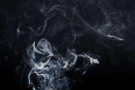 Smoke floating in the air on dark backgroundの写真素材