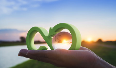 Globe glass on hand with sunrise at river bank.Sustainable of energy and businessの写真素材