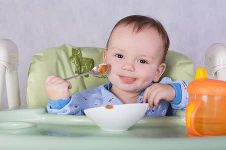 child is eating sitting at table, isolated over whiteの写真素材