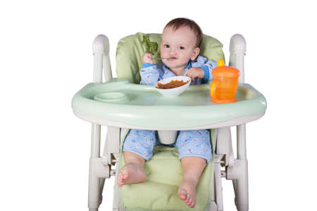 child is eating sitting at table, isolated over whiteの写真素材