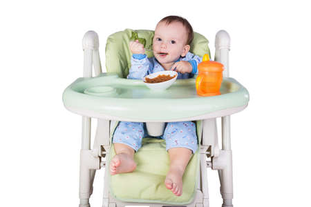 child is eating sitting at table, isolated over whiteの写真素材