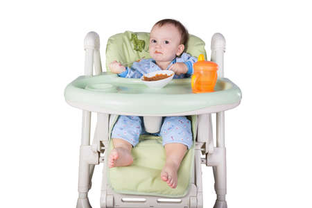 child is eating sitting at table, isolated over whiteの写真素材