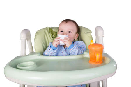 child is eating sitting at table, isolated over whiteの写真素材
