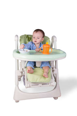 child is eating sitting at table, isolated over whiteの写真素材