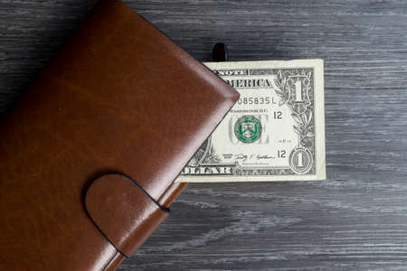 Money series : One dollar banknote in long brown wallet on black wooden tableの写真素材